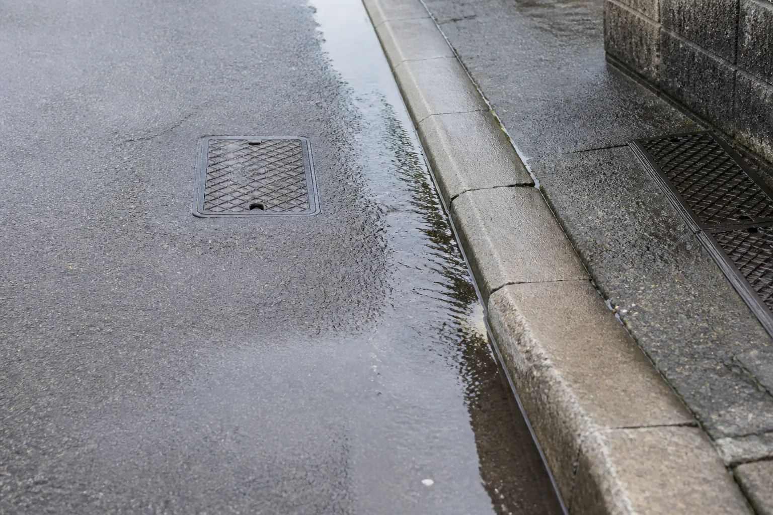 住宅敷地外の道路縁石付近から水が出ている状況