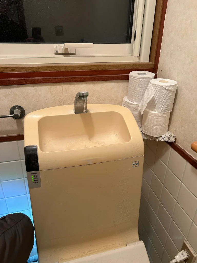 トイレタンク上の手洗い蛇口から水が止まらない様子