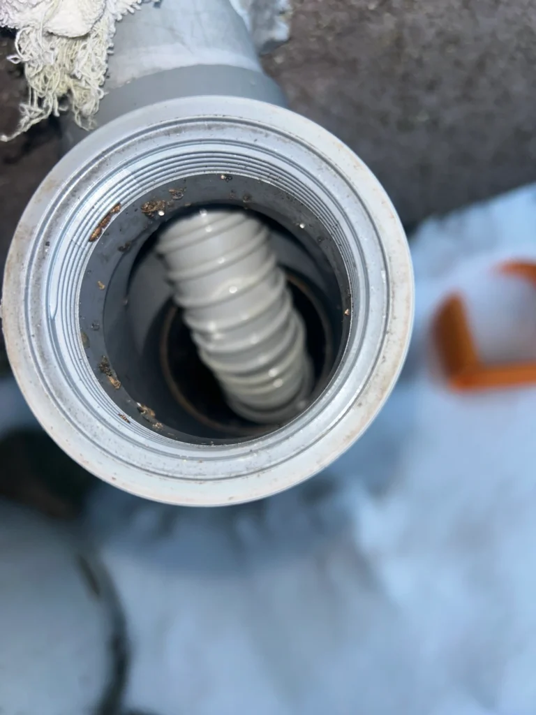 キッチン下蛇腹ホースを壁外の排水管に無理くり突っ込んでいる状態の写真